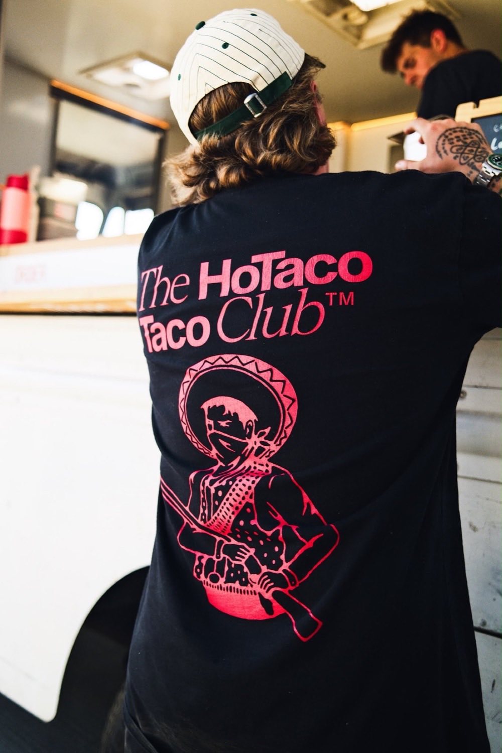 The back of a HoTaco Taco Club shirt worn by a member of the crew working inside the truck.