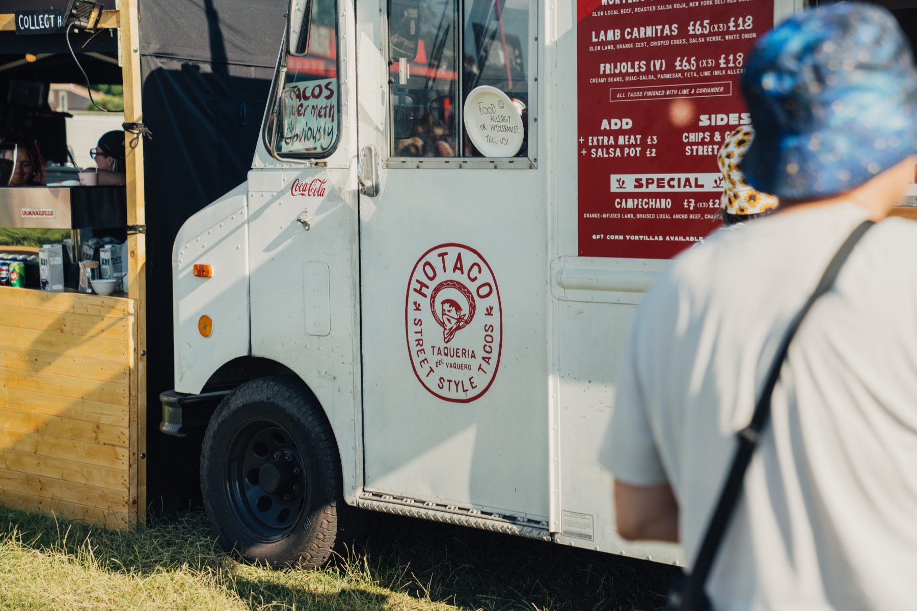 The side of the step van with the Taqueria del Vaquero roundel and the menu board, a customer at the hatch.